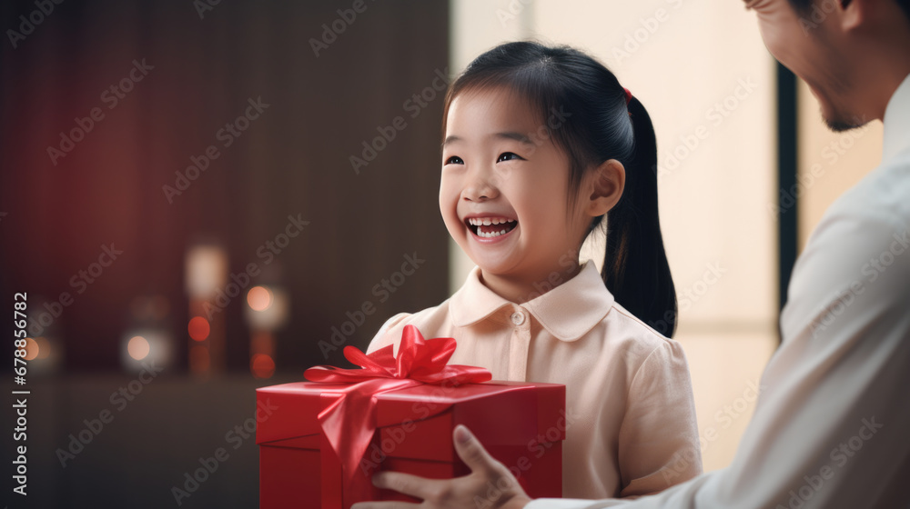 A father and daughter are sharing a joyful moment as they hold a festively wrapped Christmas gift A father and daughter are sharing a joyful moment as they hold a festively wrapped Christmas gift