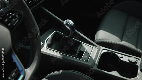 six-speed gear shift knob close-up in the interior of modern sports car black leather blue stitching cup holder chair buttons
