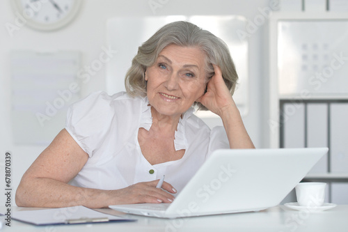 elderly woman working with a laptop on a white background