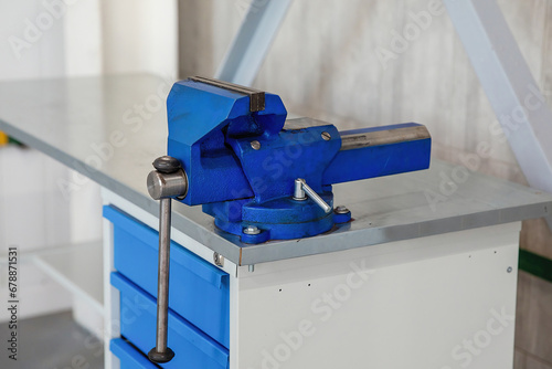 Blue metal vise on the workbench. Locksmith tools.