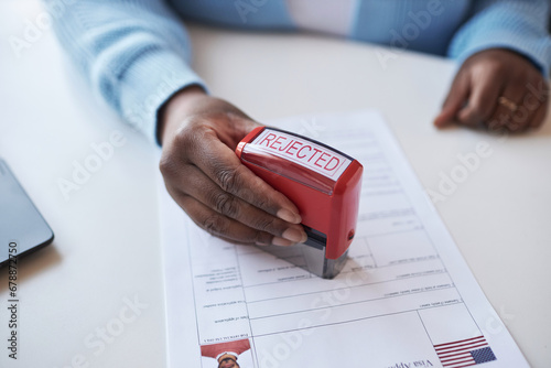 Hand of young African American female worker of visa application center stamping document while rejecting request of applicant photo