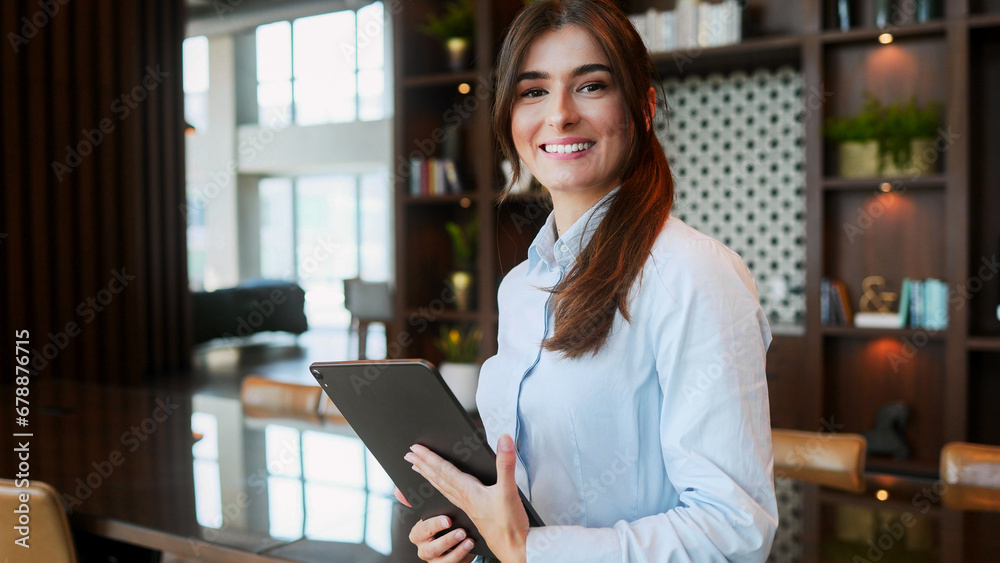 Close-up portrait of attractive successful businesswoman using tablet and wearing formal suit. Professional cheerful female employers smiling while looking at camera.