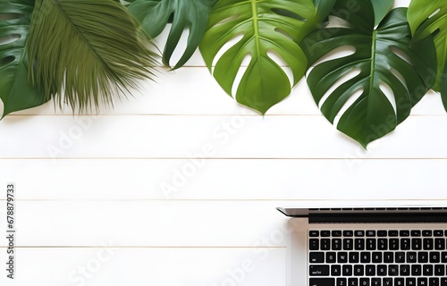 computer laptop keyboard over green monstera leaves on white wooden table for business work place card decor