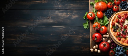 In the old wooden background a blue and red table is set with a variety of healthy foods including organic vegetables fruits and a tomato salad theres even a mouthwatering pizza photo