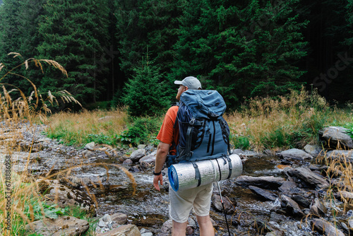 Traveling man walking in mountains with trekking pole