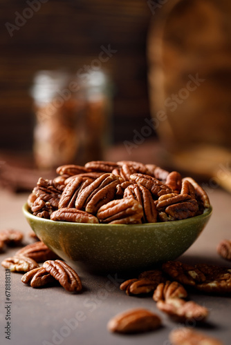 Pecan nuts in a bowl on a brown background