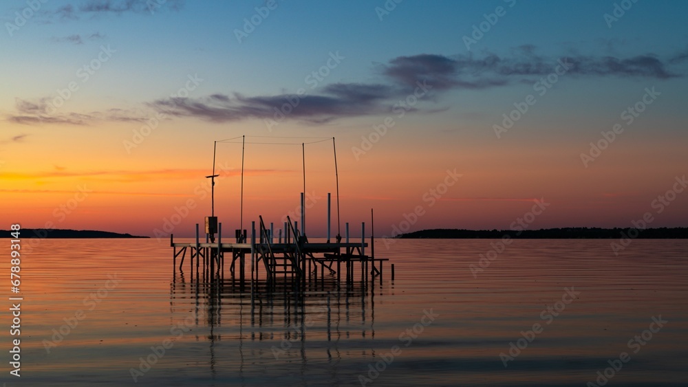 Dock in peaceful lake at vibrant sunset
