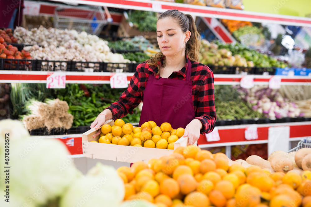 Positive european woman owner on grocery store offering for sale fresh yellow plums