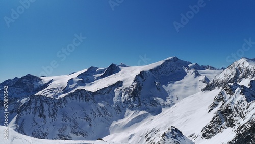 Aerial view of snowy rocky mountains on blue sky background