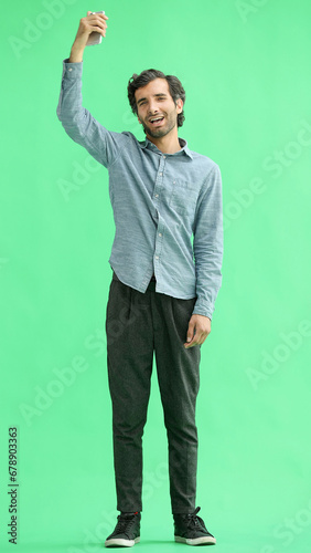 young man in full growth. isolated on green background rejoices