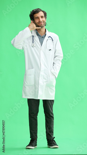 male doctor in a white coat on a green background shows a call sign