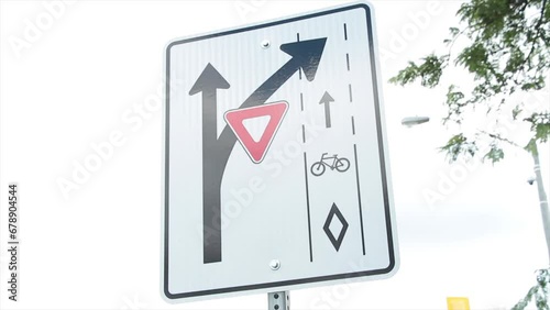 bike bicycle lane turn branch off bend yield rectangle traffic sign white black red with sky and tree branches behind photo