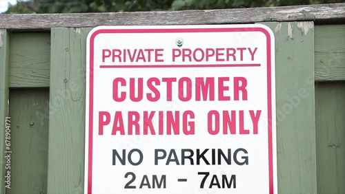 private property customer parking only no parking 2am to 7am on green wood picket fence, white red black photo