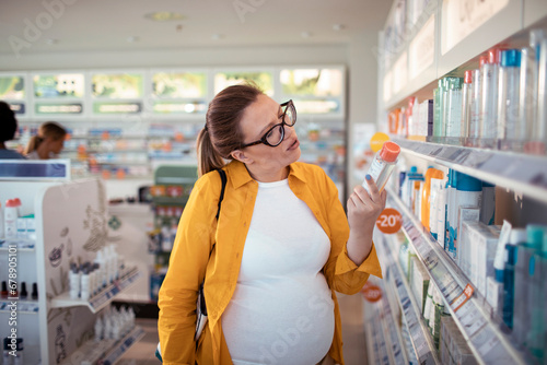Pregnant woman choosing product at pharmacy drugstore photo
