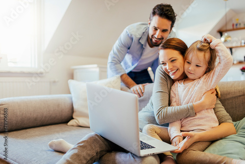 Young family looking at laptop on the couch at home © Geber86