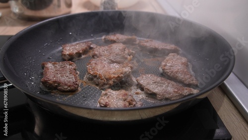 Dolly shot of Brown Steaks Grilling in Pan with Steam.