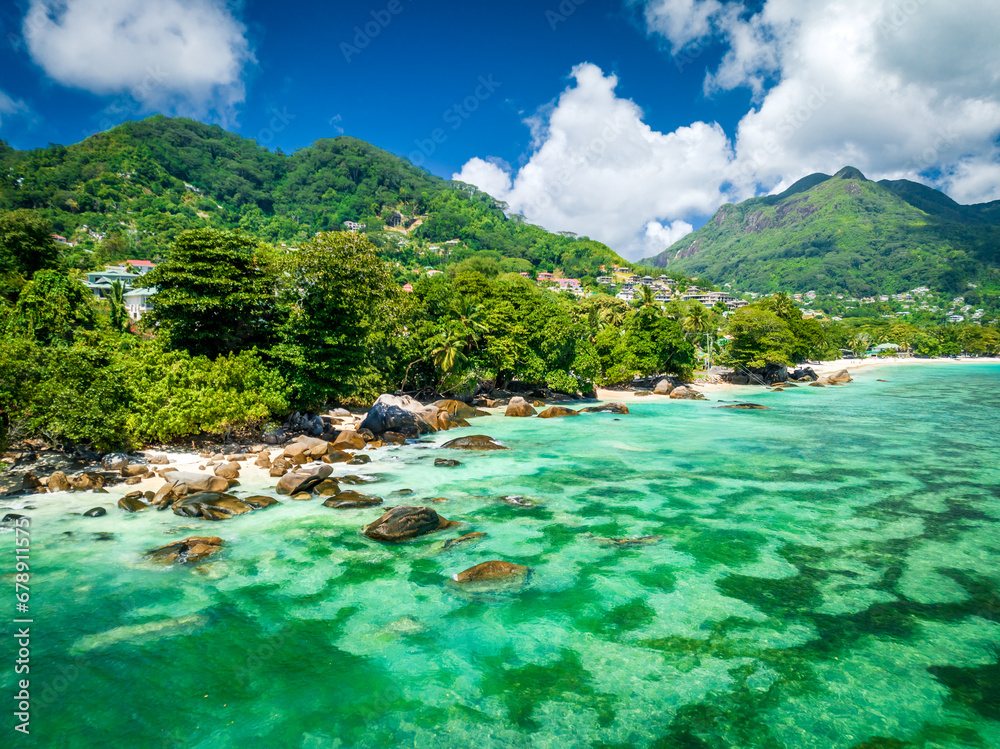 Fototapeta premium Landscape on a tropical island. Granite rocks, turquoise ocean water, tropical forest. Typical landscape on Mahe island, Seychelles. Natural landscape, vacation picture, travel banner