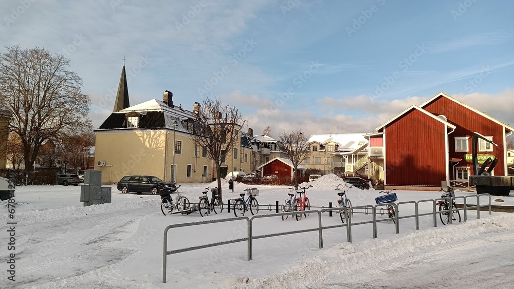 View of red and white buildings and a yard covered by snow full of bicycles in Norberg, Sweden.