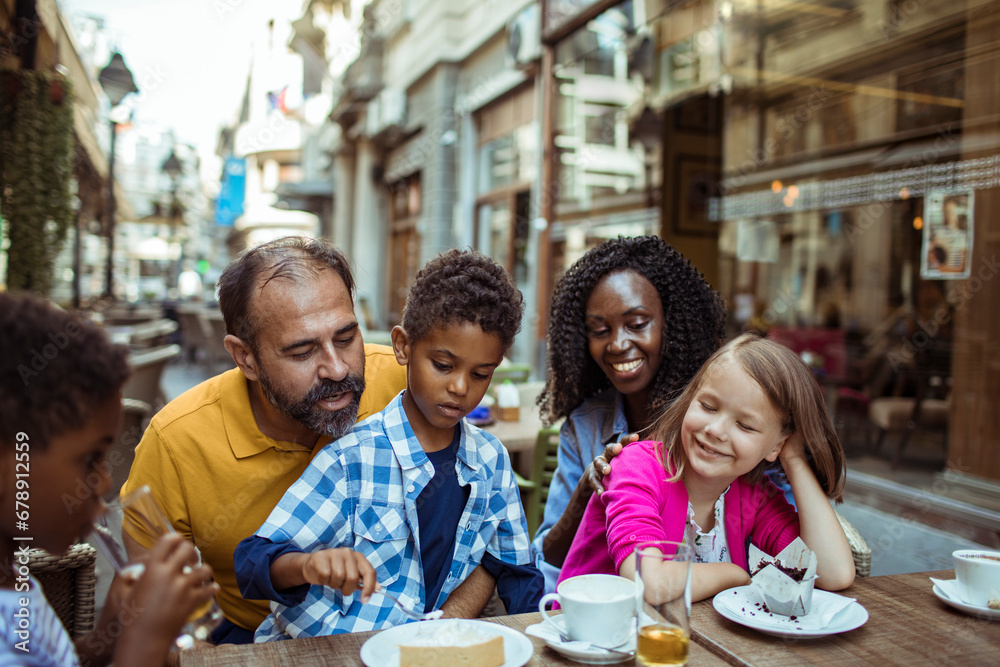 Young interracial family sitting in outdoor cafe in city Young interracial family sitting in outdoor cafe in city