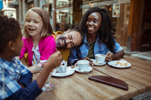 Young interracial family sitting in outdoor cafe in city © Vorda Berge