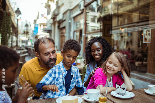 Young interracial family sitting in outdoor cafe in city