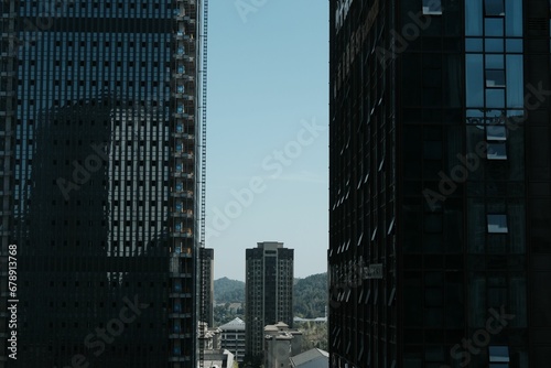Aerial view of a building seen through large dark modern buildings in the city © Wirestock