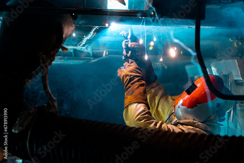 man working under a train using a welder 