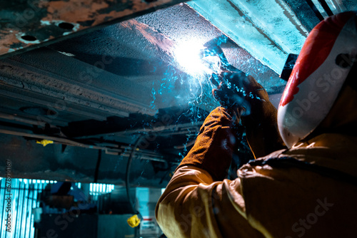 man working under a train using a welder 