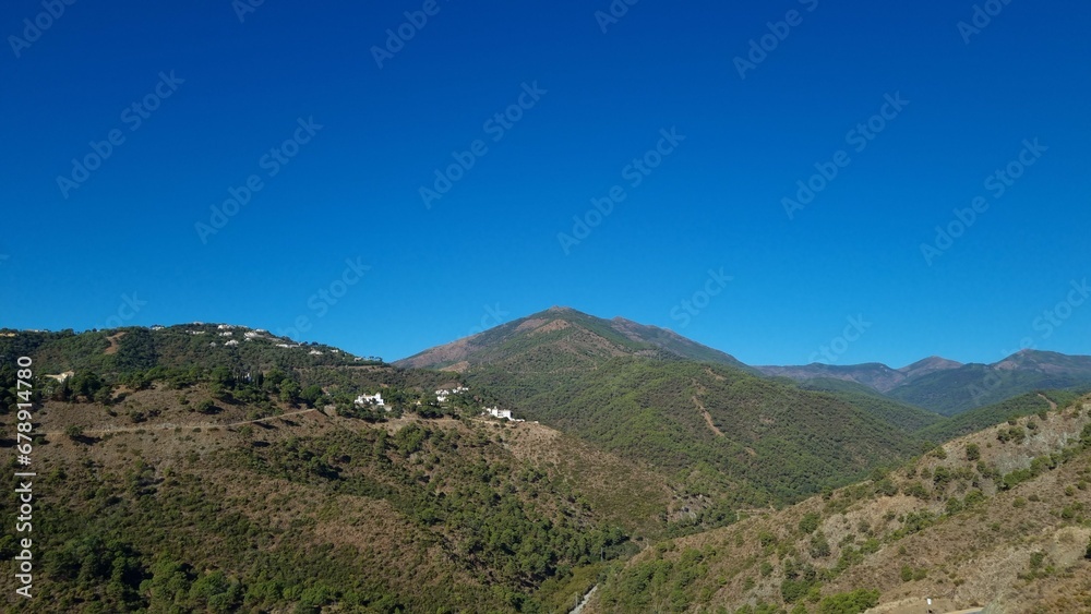 Scenic view of a mountain range covered with green shrubs on a sunny day