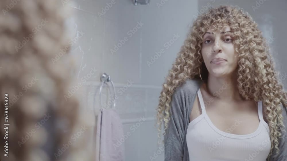 Vista traseira e reflexo facial de uma jovem mulher transexual se olhando no espelho do banheiro. Cinematico 4k.