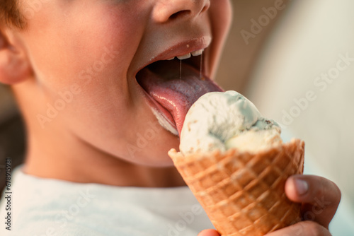 Close-up view of a boy eating ice cream in a waffle cup. Macro. Detailed view of a tongue in ice cream, Summer time, happy childhood. High quality photo photo