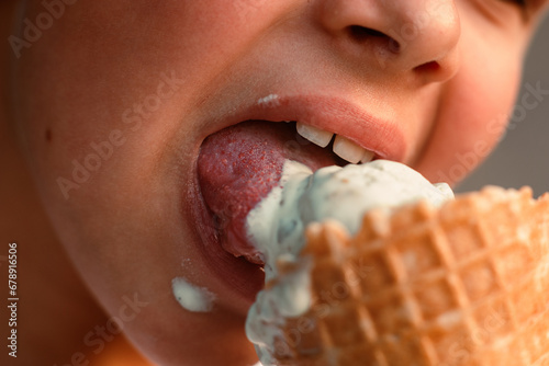 Close-up view of a boy eating ice cream in a waffle cup. Macro. Detailed view of a tongue in ice cream, Summer time, happy childhood. High quality photo