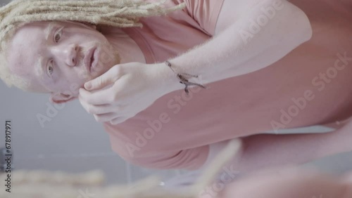 Homem albino com penteado afro aplicando protetor solar no rosto. Reflexo no espelho. Cinematico 4k. Video vertical. photo
