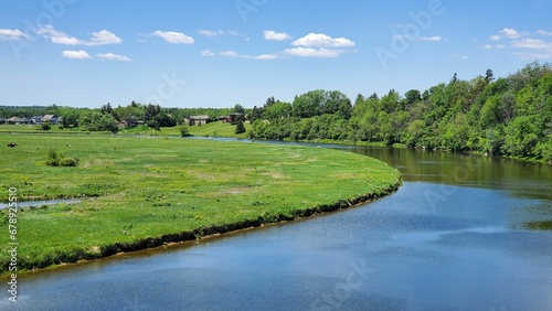 Φωτογραφία Scenic shot of a river in a green field surrounded by lush trees in St