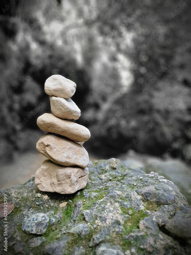 Selective focus of a stack of stones on a mossy rock against a blurred black and white background Selective focus of a stack of stones on a mossy rock against a blurred black and white background