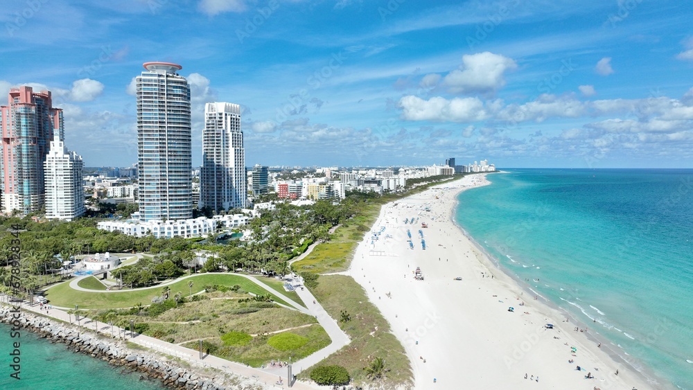 Aerial shot of the blue ocean and the sandy shore with buildings against the blue sky