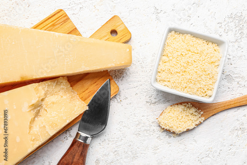 Wooden board with pieces of tasty Parmesan cheese on light background, closeup