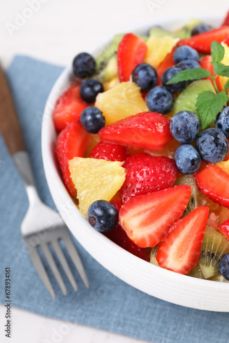 Delicious fresh fruit salad in bowl served on white table  closeup