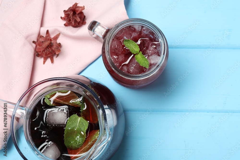 Delicious iced hibiscus tea with mint and dry flowers on light blue wooden table, flat lay. Space for text Delicious iced hibiscus tea with mint and dry flowers on light blue wooden table, flat lay. Space for text