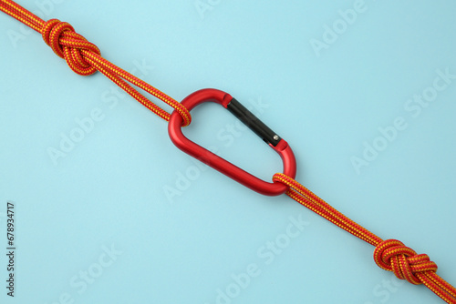 One metal carabiner with ropes on light blue background, top view
