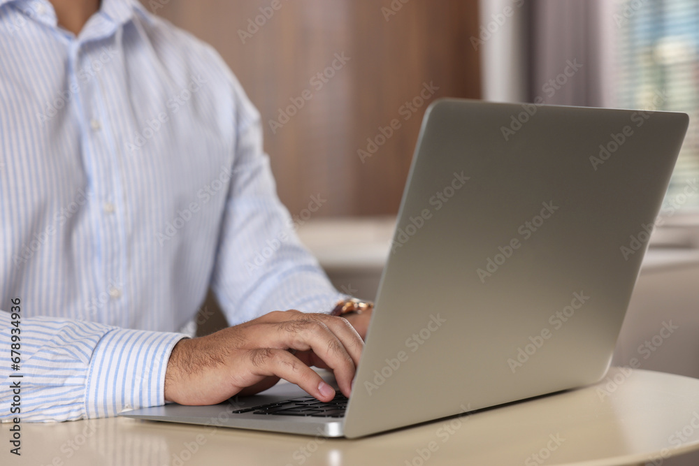 Man working on laptop at table in office, closeup Man working on laptop at table in office, closeup