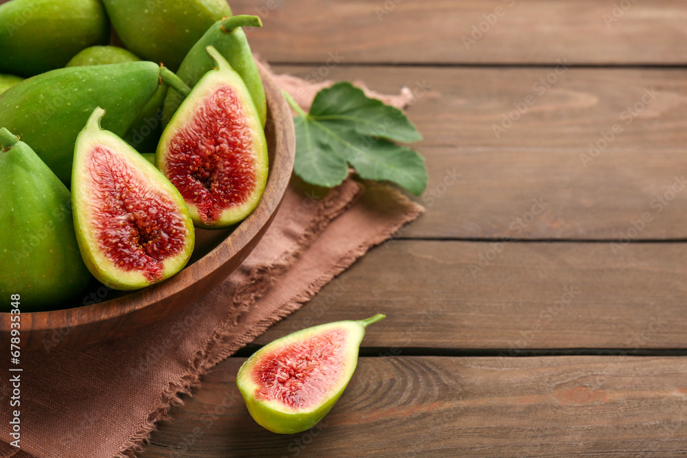 Cut and whole green figs in bowl on wooden table, closeup. Space for text Cut and whole green figs in bowl on wooden table, closeup. Space for text