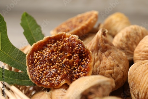 Tasty dried figs and green leaf in wicker basket, closeup