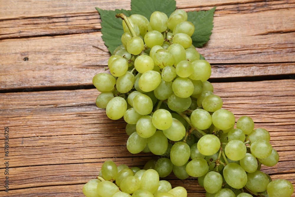 Delicious fresh green grapes and leaves on wooden table, above view Delicious fresh green grapes and leaves on wooden table, above view