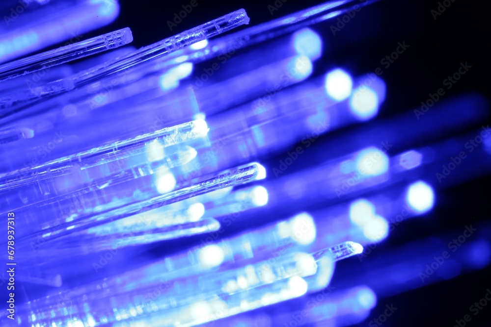 Optical fiber strands transmitting blue light in darkness, macro view