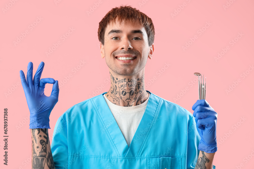 Male dentist with tools showing OK on pink background Male dentist with tools showing OK on pink background