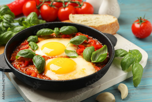 Delicious Shakshuka served on light blue wooden table, closeup
