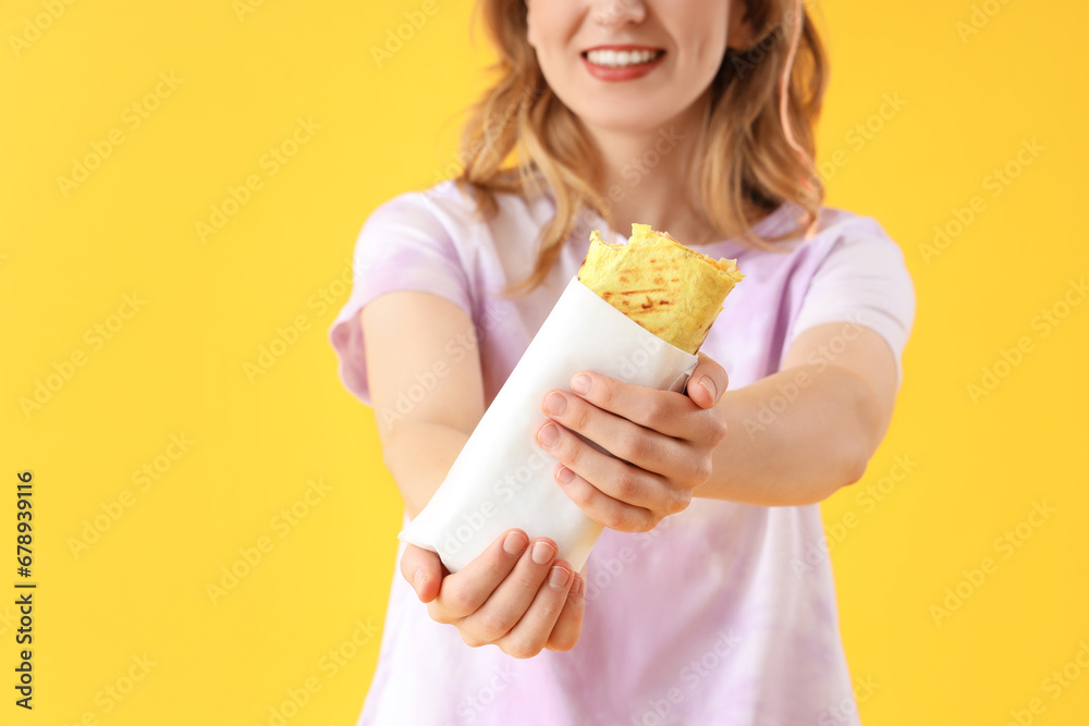 Young woman with tasty sandwich wrap on yellow background, closeup Young woman with tasty sandwich wrap on yellow background, closeup