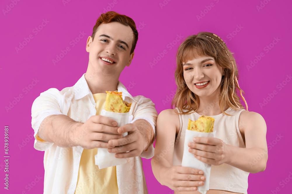 Young couple with tasty sandwich wraps on purple background Young couple with tasty sandwich wraps on purple background