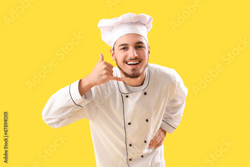 Male chef showing "call me" gesture on yellow background